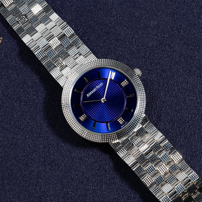 An Audemars Piguet Classic White Gold Ultra-Thin wristwatch rests on a dark textured surface.