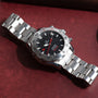 An OMEGA Seamaster 300 Professional Apnea Chronograph with a black dial and red details displayed on a red surface.