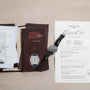 A Patek Philippe Gondolo Annual Calendar watch displayed on a beige surface with its certificate, manuals, and documents.