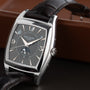 A Patek Philippe Gondolo Annual Calendar wristwatch featuring a rectangular silver case and brown leather strap, displayed on a leather surface.
