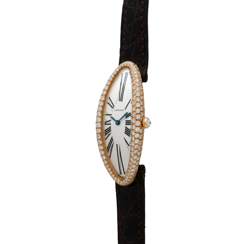 The Cartier Baignoire Allongee features an elongated oval gold case with a diamond bezel, black Roman numerals, and a black leather strap.
