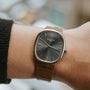 A wrist wearing the Patek Philippe Ellipse watch with a brown leather strap and black dial.