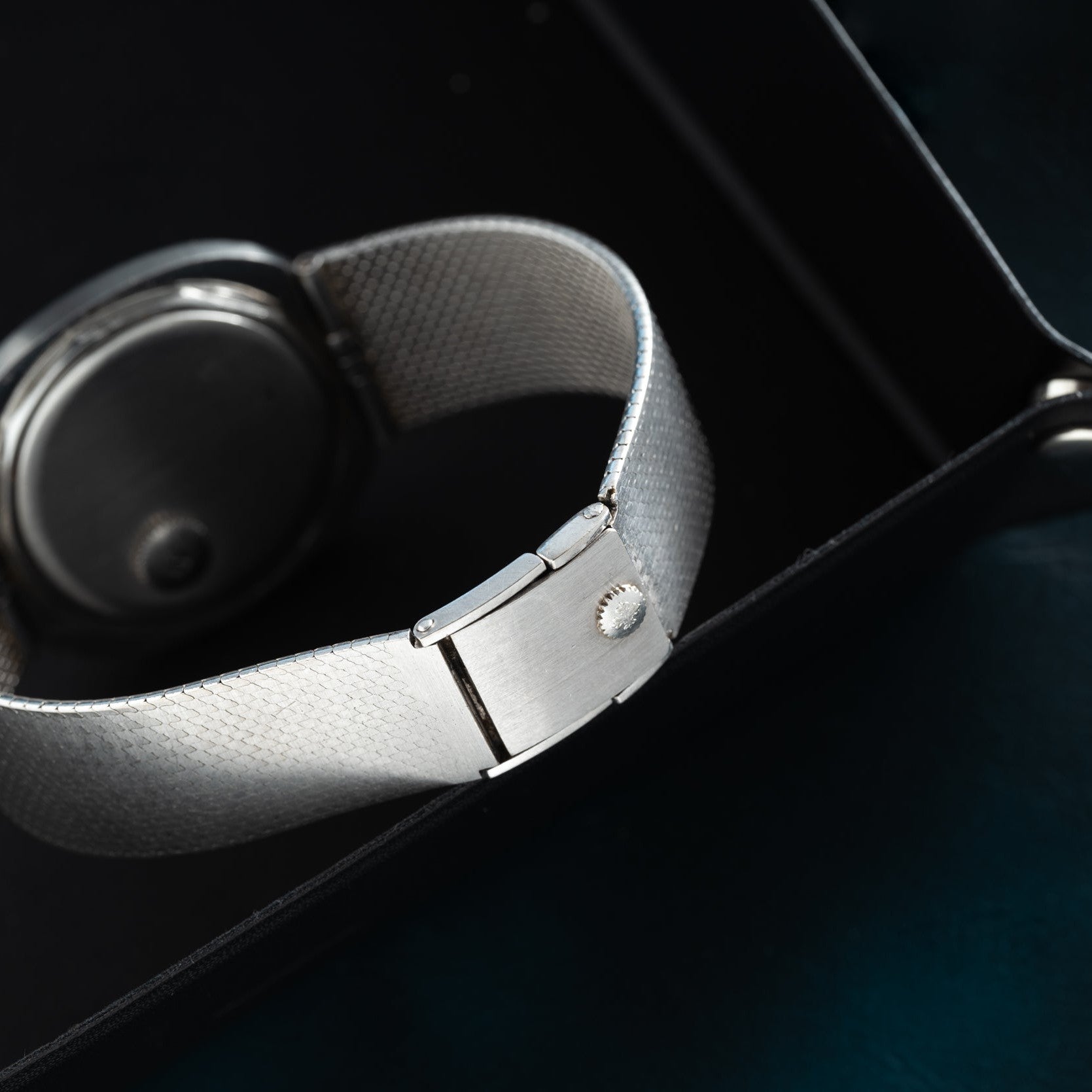 Close-up of the Patek Philippe Dress Watch UFO featuring a silver mesh band with clasp, resting on the edge of a black tray.