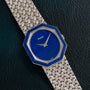 Piaget Lapis Lazuli White Gold Dress Watch with a hexagonal blue face and woven metal band displayed on a dark textured surface.
