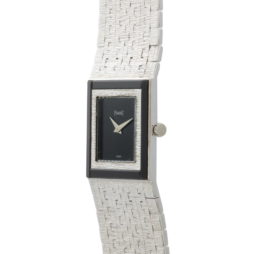 A Piaget White Gold Onyx Dress Watch featuring a rectangular case, black dial, and textured metal band.