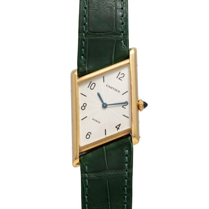 Cartier Tank Asymétrique watch with a skewed square gold case, white dial, and green leather strap.