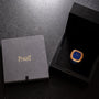 A Piaget Black Tie Andy Warhol gold and blue watch in a black box sits beside a closed Piaget case on a dark surface.