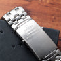 A close-up of an OMEGA Seamaster 300 Professional GMT stainless steel watch bracelet on a dark textured surface.