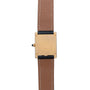 The Cartier Tank Louis watch is displayed from the back in a vertical view, highlighting its gold case and brown leather strap.