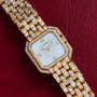 The Cartier Ceinture Paris Diamond watch, featuring diamond accents, is displayed on a red leather background.
