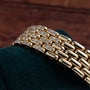 Close-up of the Cartier Ceinture Paris Diamond bracelet, featuring rows of sparkling diamonds, resting on dark green fabric.