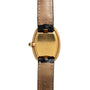 Cartier Baignoire watch featuring a gold case, black crown, and tan leather strap, shown from the back.