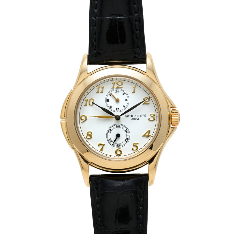 The Patek Philippe Calatrava Travel Time features a white dial with two subdials and a black leather strap.