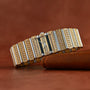 The Piaget Polo Pave, a luxurious gold and silver diamond-encrusted wristwatch, rests on a brown leather surface.