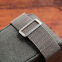 A close-up of the Cartier Santos Platinum’s silver mesh strap on a green textured surface, set against a blurred brown background.