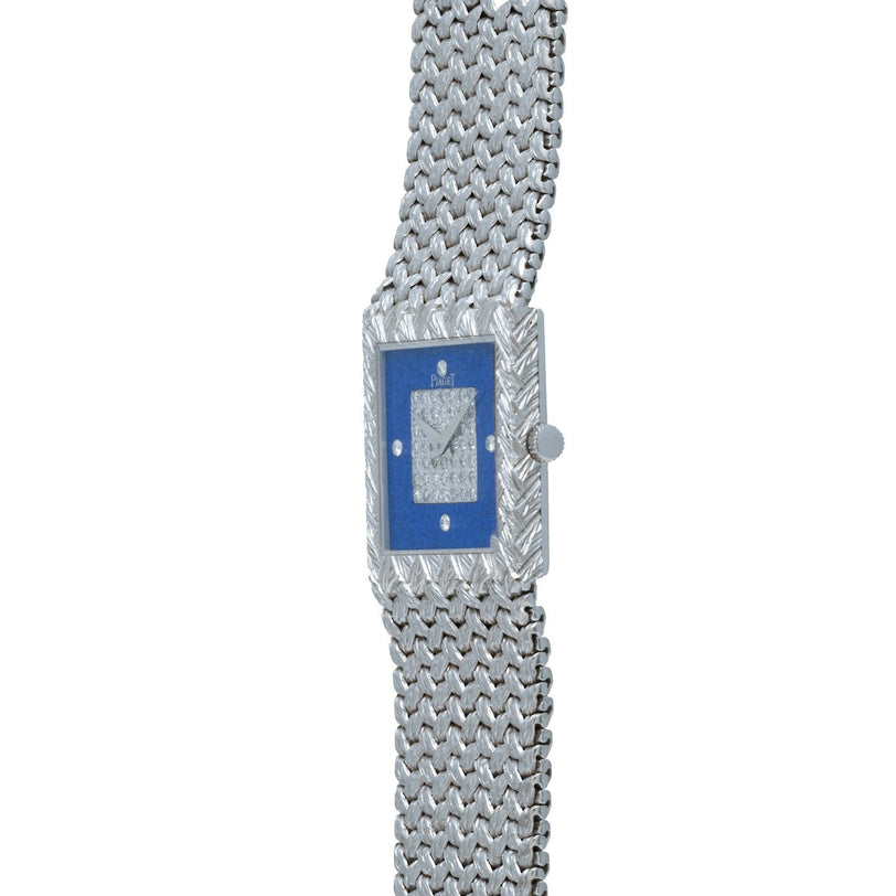 The Piaget Tradition Lapis Lazuli Diamond Dress Watch is a luxury silver wristwatch featuring a blue rectangular face and a textured metal band.