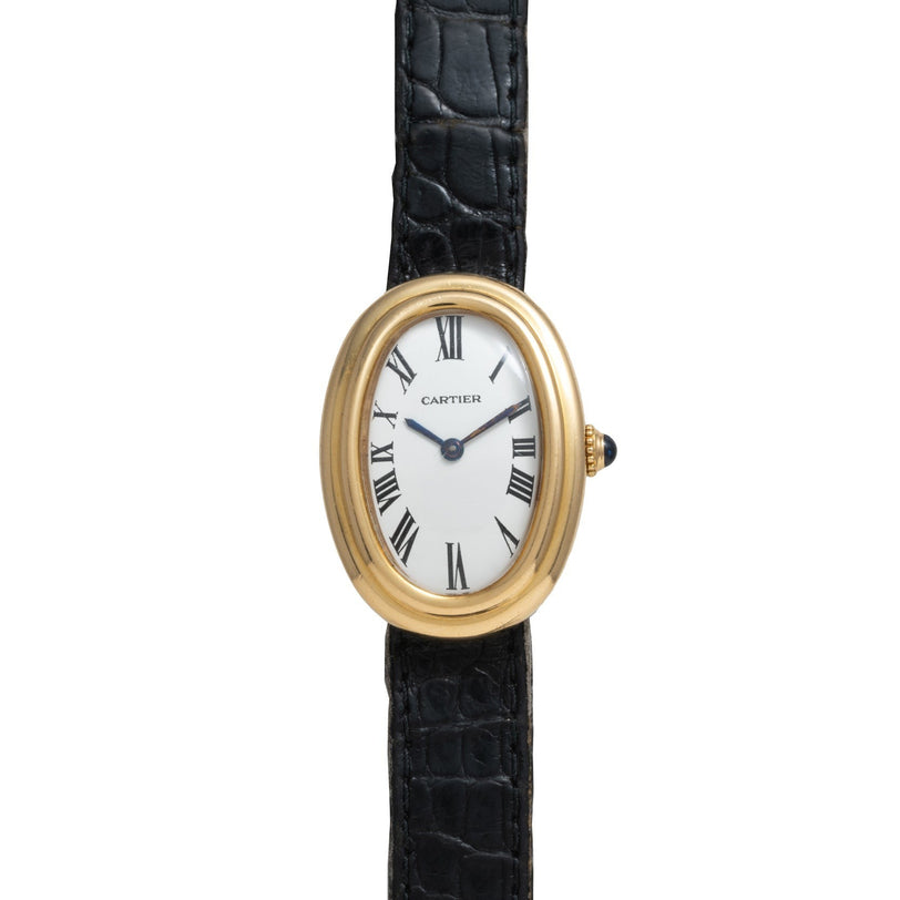 The Cartier Baignoire is a gold oval watch featuring a white face with black Roman numerals and a black leather strap.