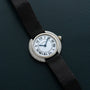The Cartier Vendome Diamond watch features Roman numerals and a black strap, displayed on a dark textured surface.