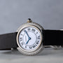A Cartier Vendome Diamond watch with Roman numerals, a diamond bezel, and a black strap is shown on a gray background.