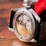 A close-up of the Patek Philippe Annual Calendar Moonphase’s exposed mechanical movement on a wooden surface.