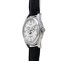 The Patek Philippe Annual Calendar Moonphase, featuring a silver case, white dial, black leather strap, and date display, is shown at an angle.