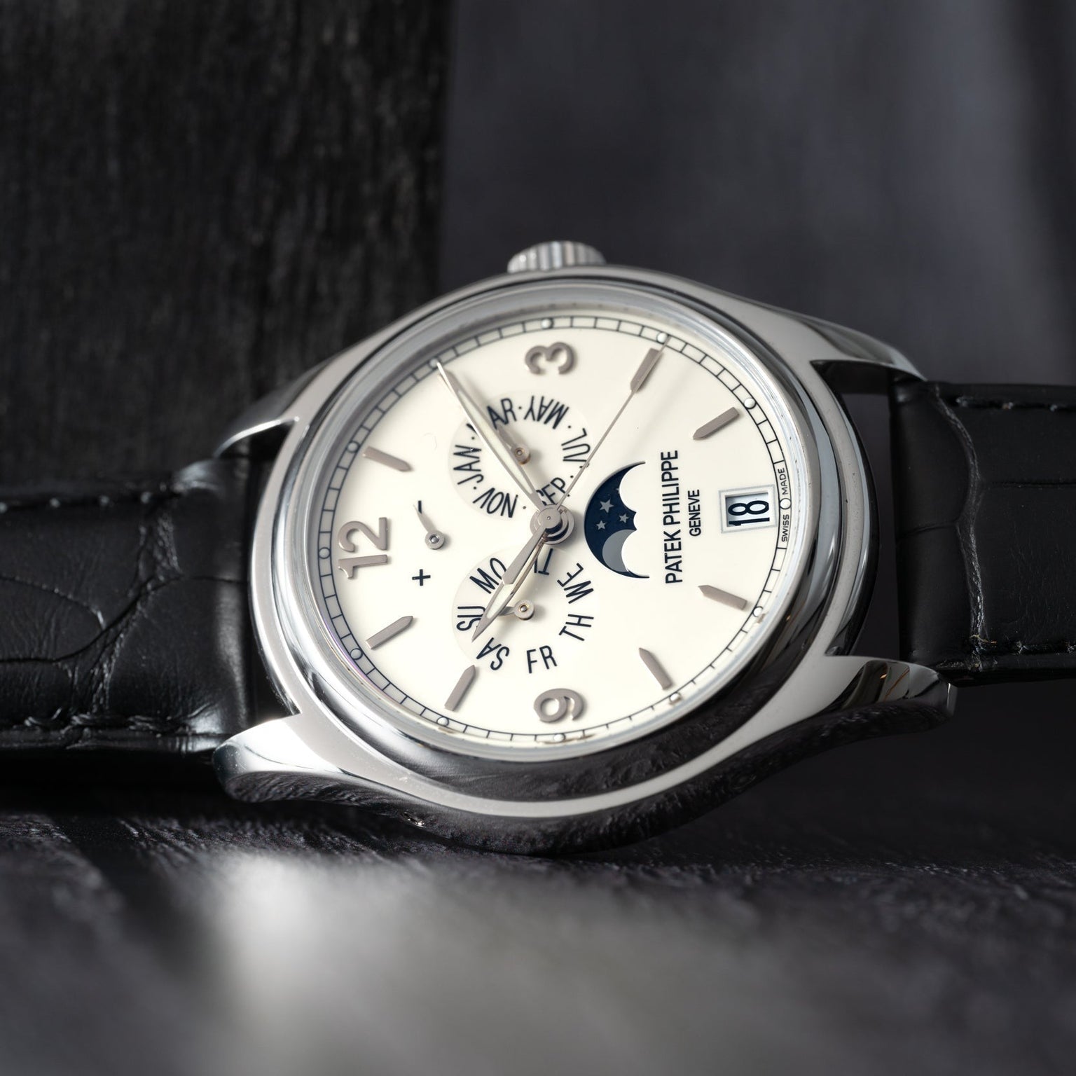 The Patek Philippe Annual Calendar Moonphase is a luxury wristwatch with a leather strap featuring date, day, month, and moon phase displays on its dial.