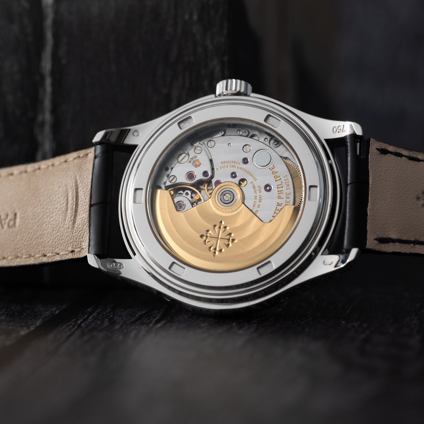 A close-up of the back of the Patek Philippe Annual Calendar Moonphase, showcasing its exposed mechanical movement and leather strap.