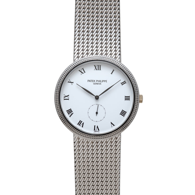 The Patek Philippe Calatrava is a silver watch with a white face, Roman numerals, and a mesh metal band.