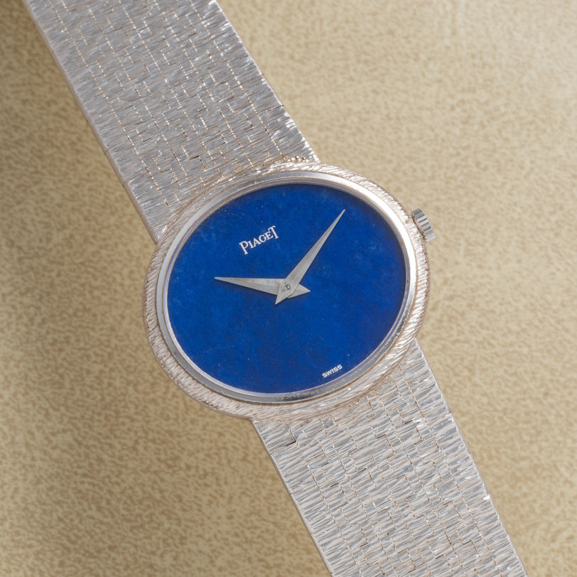 A Piaget White Gold Lapis Lazuli Dress Watch with a blue lapis dial, displayed on a beige background.