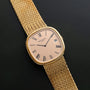 Patek Philippe Ellipse Jumbo watch with Roman numerals on a woven gold band, displayed on a black surface.