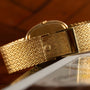 Close-up of the Patek Philippe Ellipse Jumbo gold wristwatch with a textured band, resting on a glossy magazine surface.