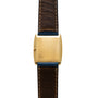 The Cartier Protocole gold rectangular watch features a brown leather strap, shown from the back with a plain case and visible stitching.