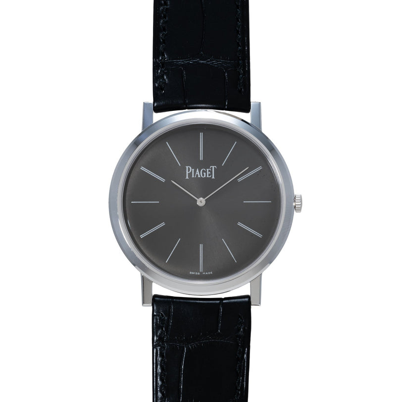 The Piaget Altiplano wristwatch features a black leather strap, a black dial, and silver hour markers and hands.