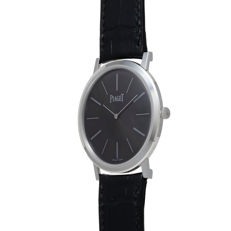 The Piaget Altiplano wristwatch features a minimalist black dial and a black leather strap, set against a white background.
