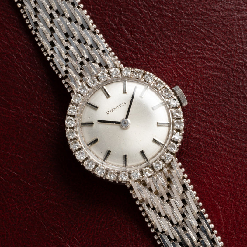 Zenith Ladies Cocktail Watch featuring a diamond-studded bezel and textured metal band, displayed on red leather.