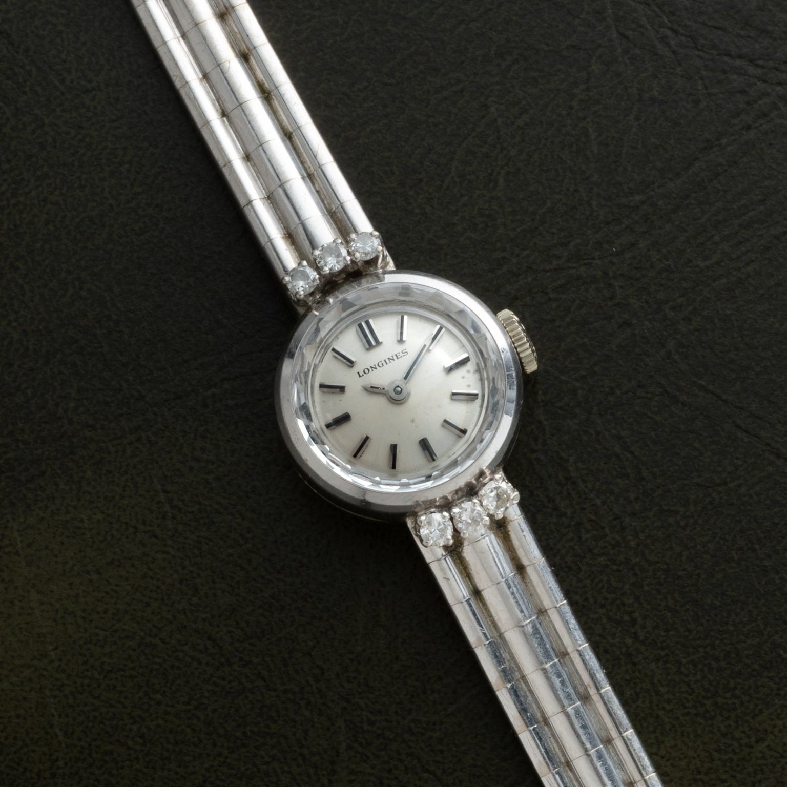 A Longines Diamond Cocktail Watch for women with a silver band and diamond accents, displayed on a dark background.