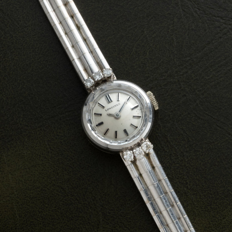 A Longines Diamond Cocktail Watch for women with a silver band and diamond accents, displayed on a dark background.