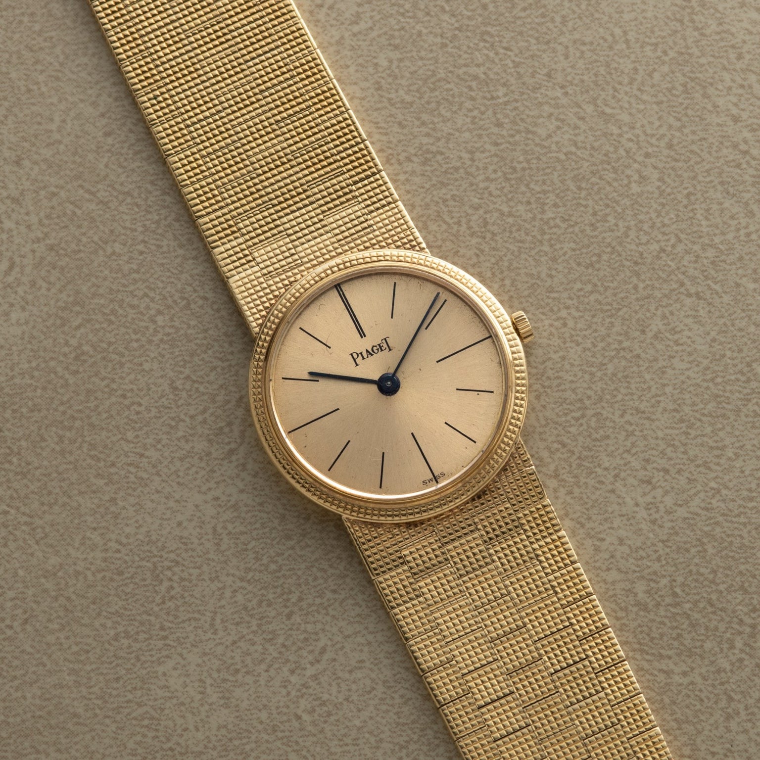 A Piaget 18K Yellow Gold Dress Watch featuring a mesh band and minimalist black hour markers on a beige dial.