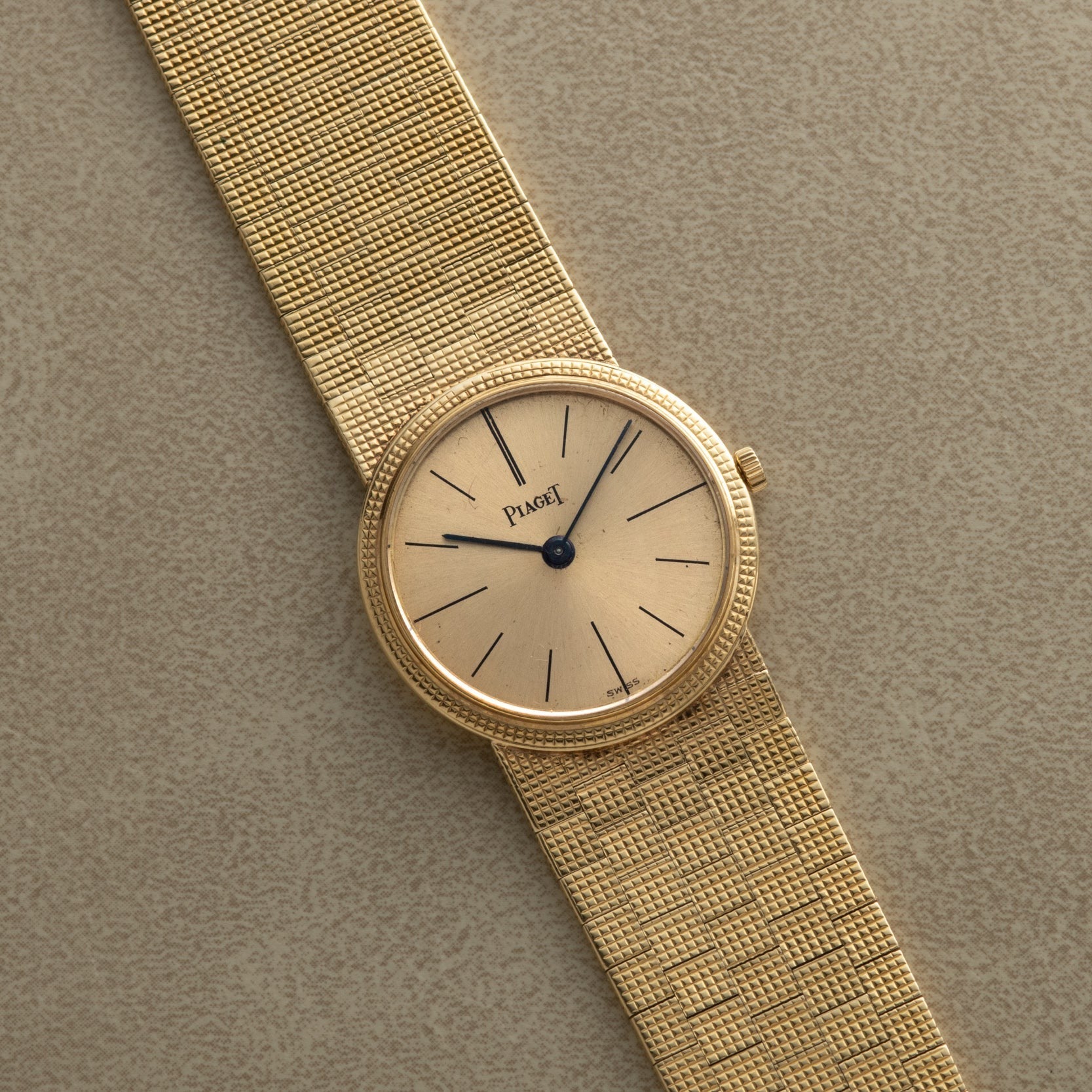 A Piaget 18K Yellow Gold Dress Watch featuring a mesh band and minimalist black hour markers on a beige dial.