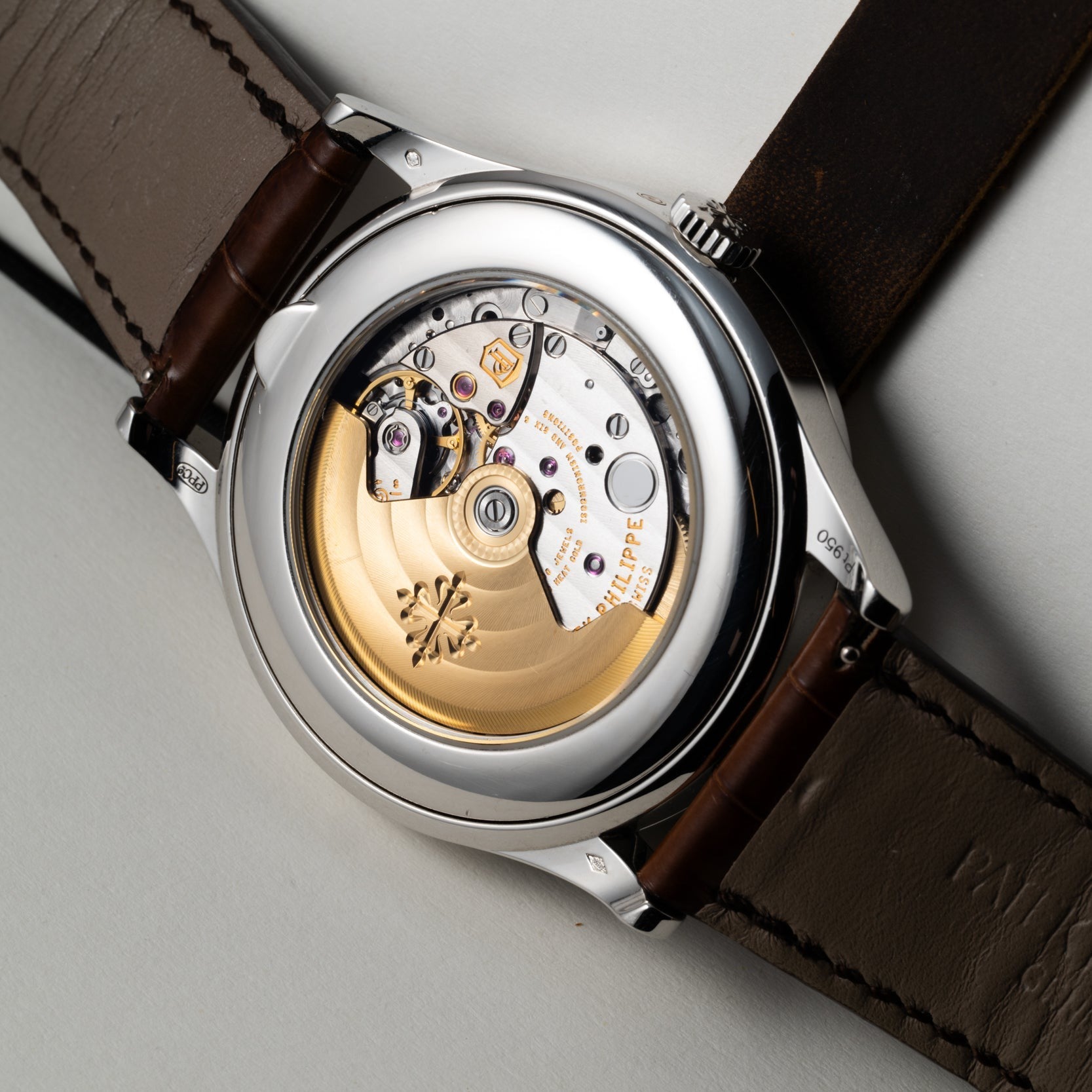 Close-up of the Patek Philippe Retrograde Perpetual Calendar’s exposed mechanical movement with a gold rotor, brown leather strap visible.
