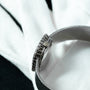 Close-up of the Patek Philippe Ellipse Ladies Dress Watch with a silver metal band, shown on a white and black fabric background.