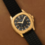 Patek Philippe Aquanaut with a black dial and strap, displayed on a brown leather surface.