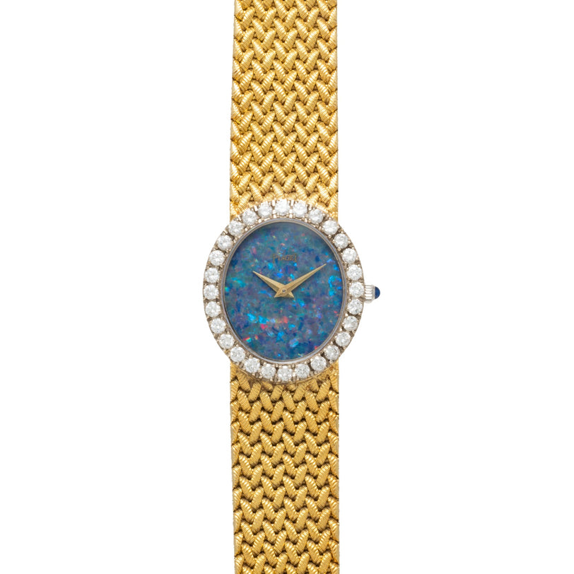 The Piaget Opal Yellow Gold Dress Watch features a blue opal face, diamond bezel, and woven yellow gold band, shown from above.