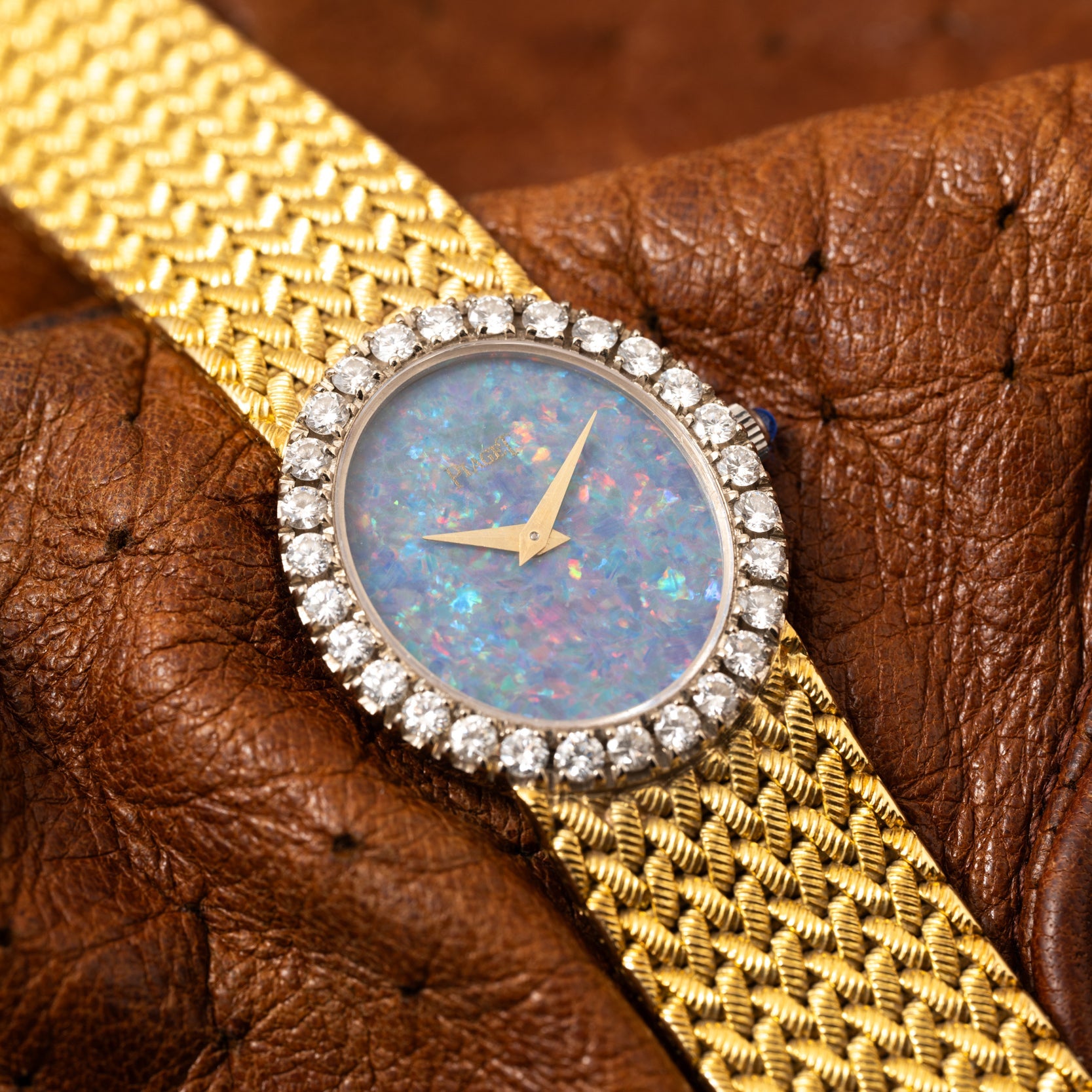 The Piaget Opal Yellow Gold Dress Watch features an opal dial and diamond bezel, elegantly displayed on textured brown leather.