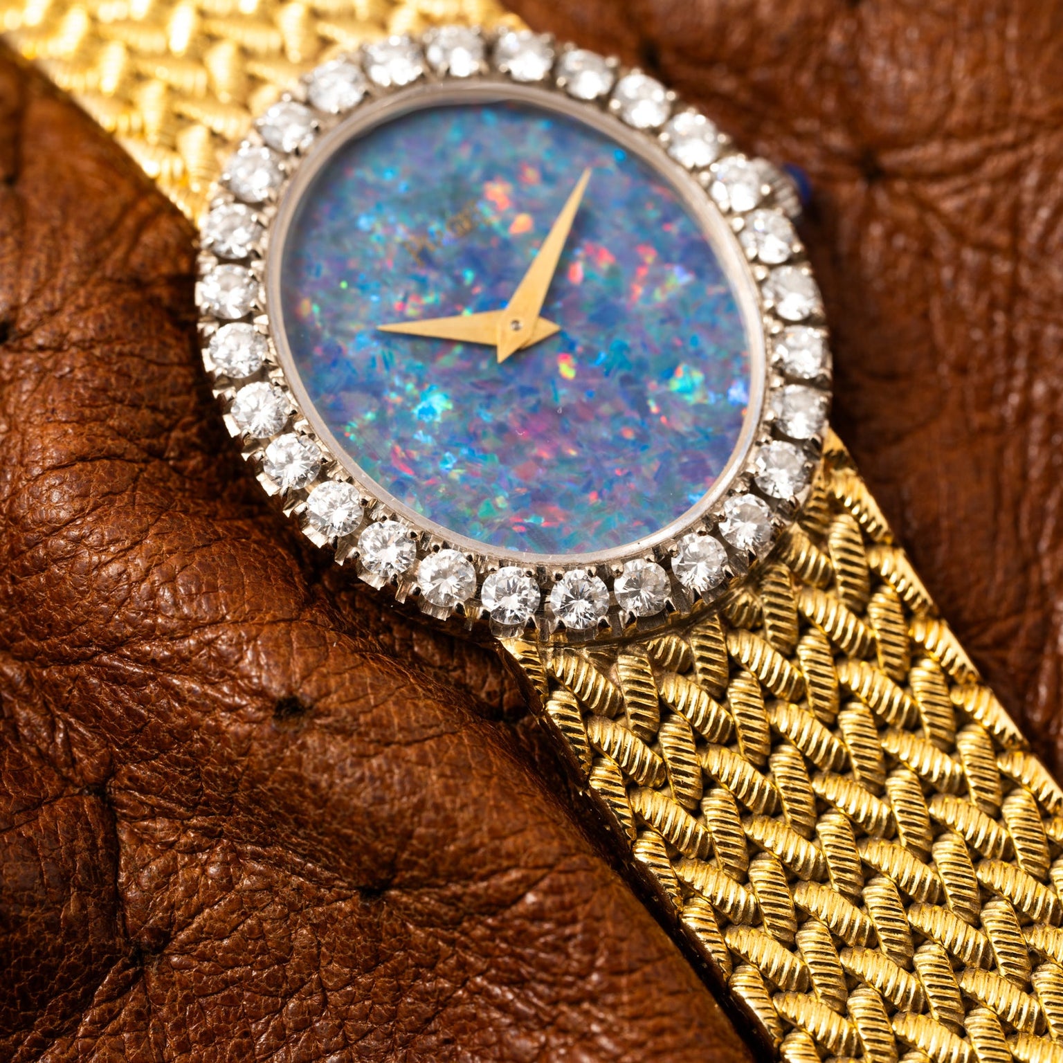 The Piaget Opal Yellow Gold Dress Watch features a blue opal face, diamond bezel, and textured brown leather strap.