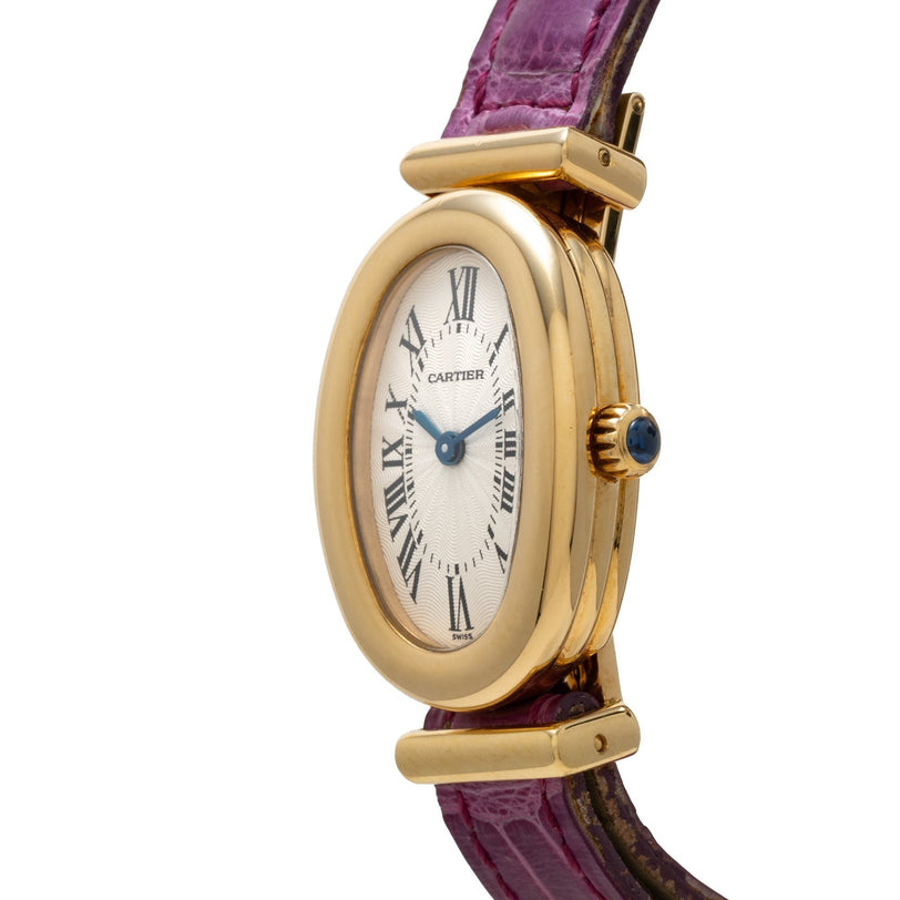 The Cartier Baignoire watch features a gold oval case, Roman numerals, blue hands, and a purple leather strap, displayed at an angle.