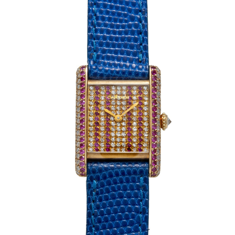The Cartier Tank Louis Diamonds is a gold rectangular watch featuring a blue lizard strap and a diamond- and ruby-encrusted face and case.