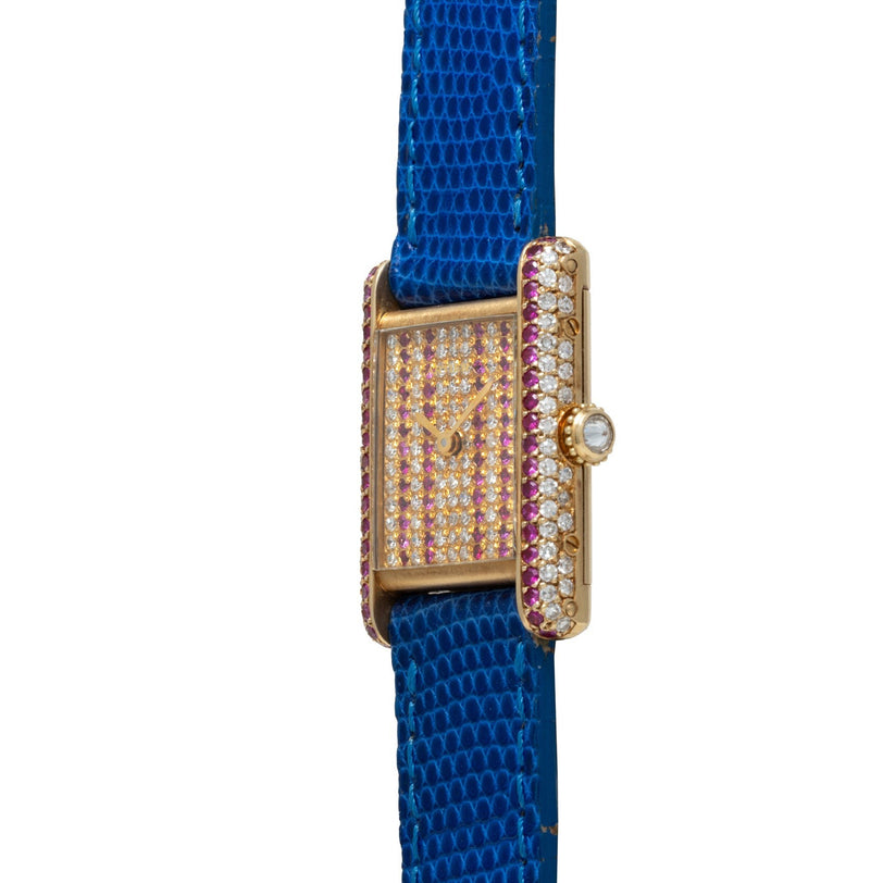 The Cartier Tank Louis Diamonds is a gold watch featuring pink gems, diamond accents, and a vibrant blue textured leather strap.