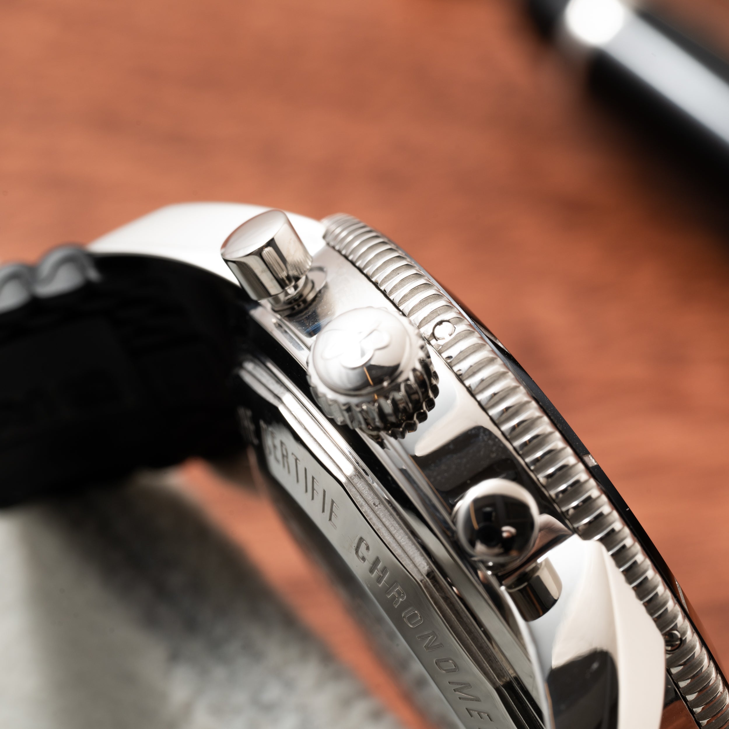 Close-up of the Breitling SuperOcean B01 Chronograph 44’s silver crown and pushers, with part of the engraved caseback in view.