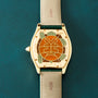 Cartier Tortue XL Turtle Limited Edition wristwatch with a leaf and plant motif engraved on the back, displayed on a green surface.